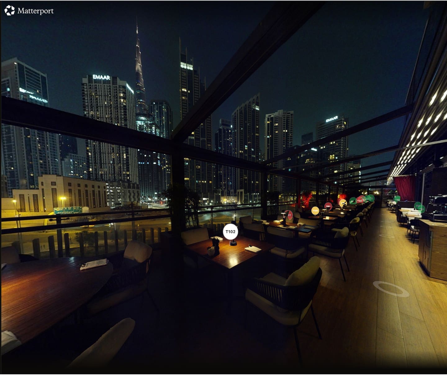 A RAYN 3D venue view of a Dubai rooftop terrace at night, each table tagged with its own marker — green for available, red for taken — with the Burj Khalifa beyond.